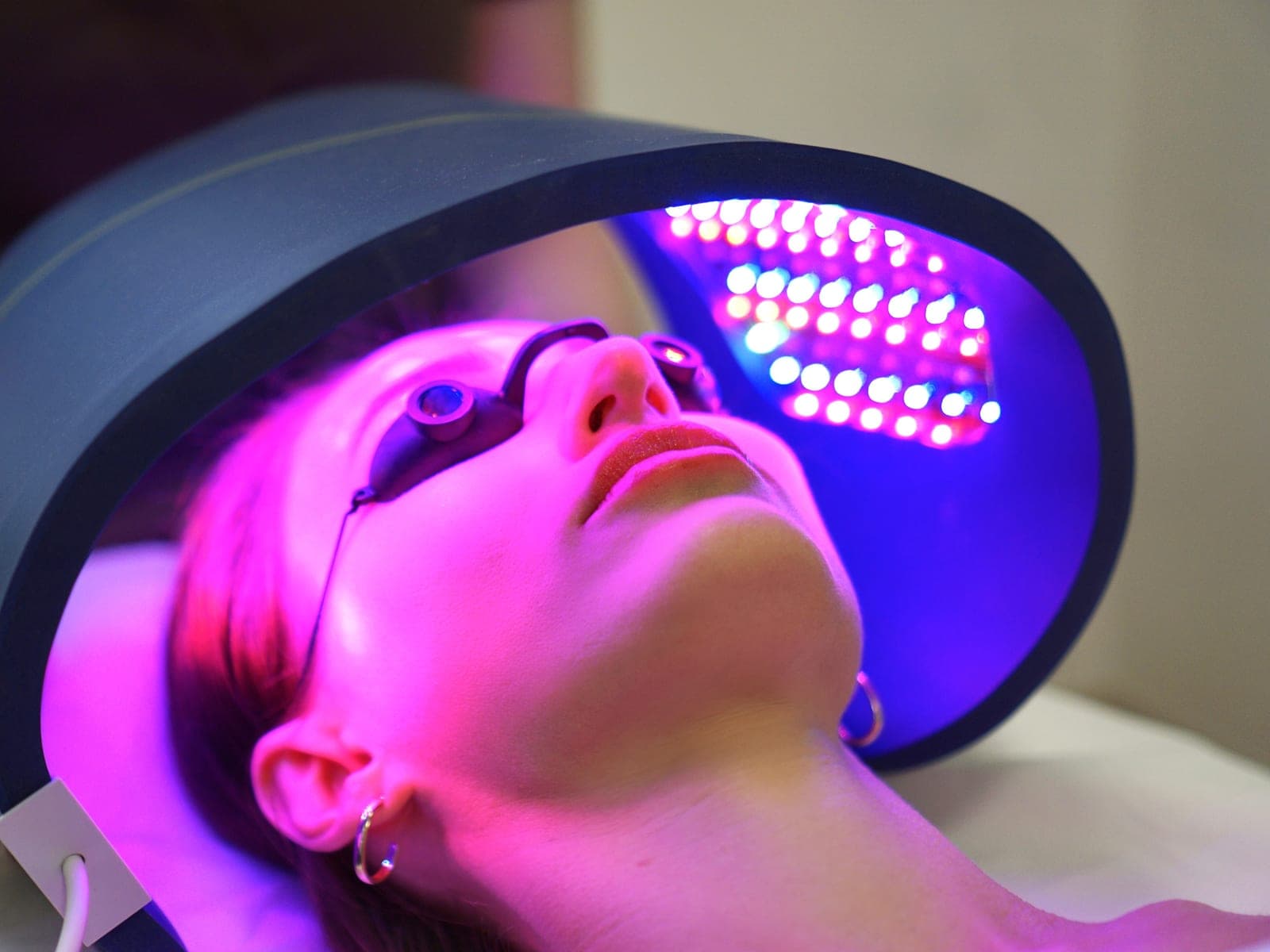 Fototerapia LED — panel diod nad twarzą pacjentki w okularach ochronnych, Kliniki Dr Kuschill MEDESTETIS