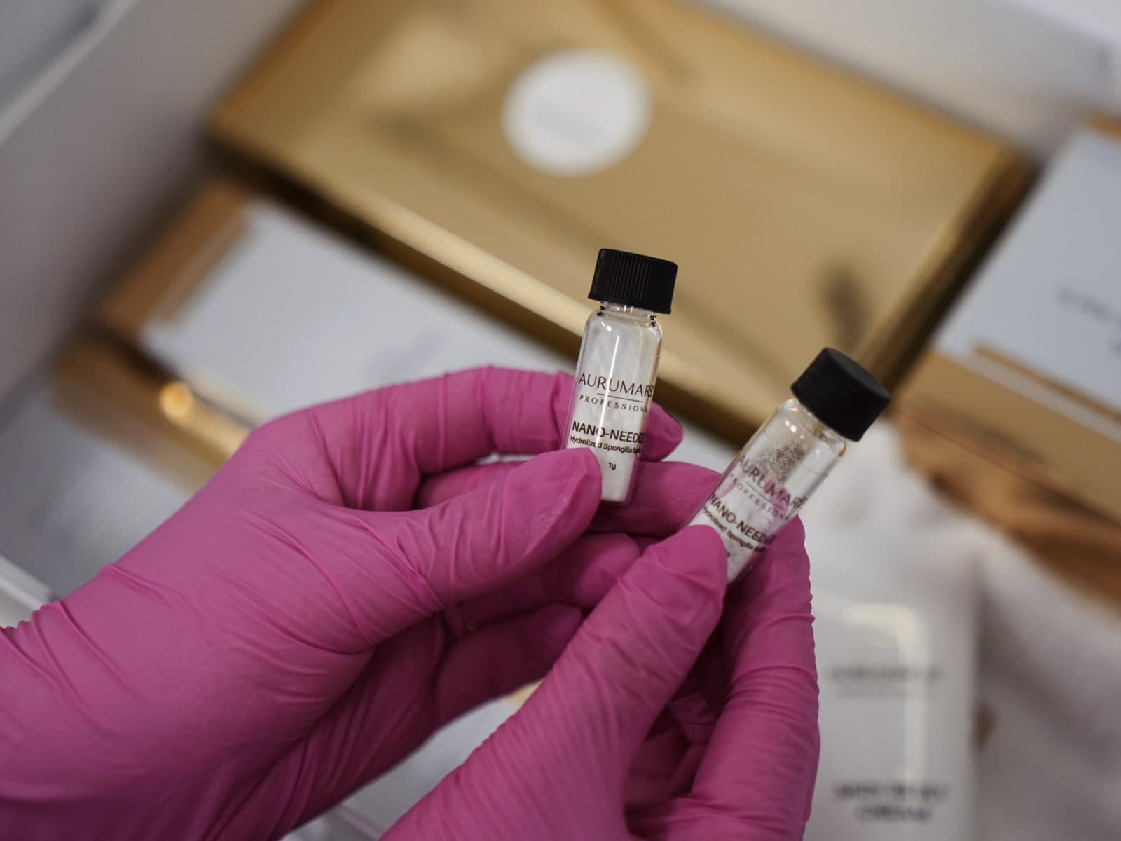 Dwie fiolki z preparatem do zabiegu nanoigłami w dłoniach w rękawiczkach — Kliniki Dr Kuschill MEDESTETIS
